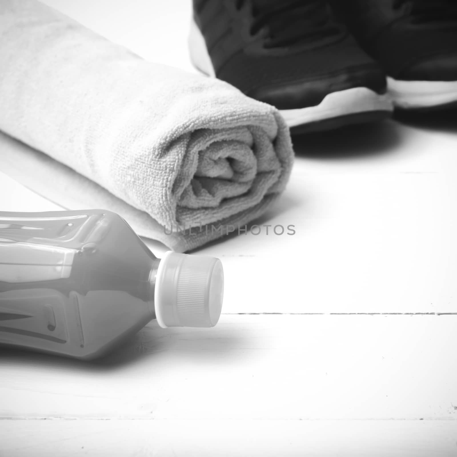 running shoes,towel and orange juice on white wood table black and white tone color style