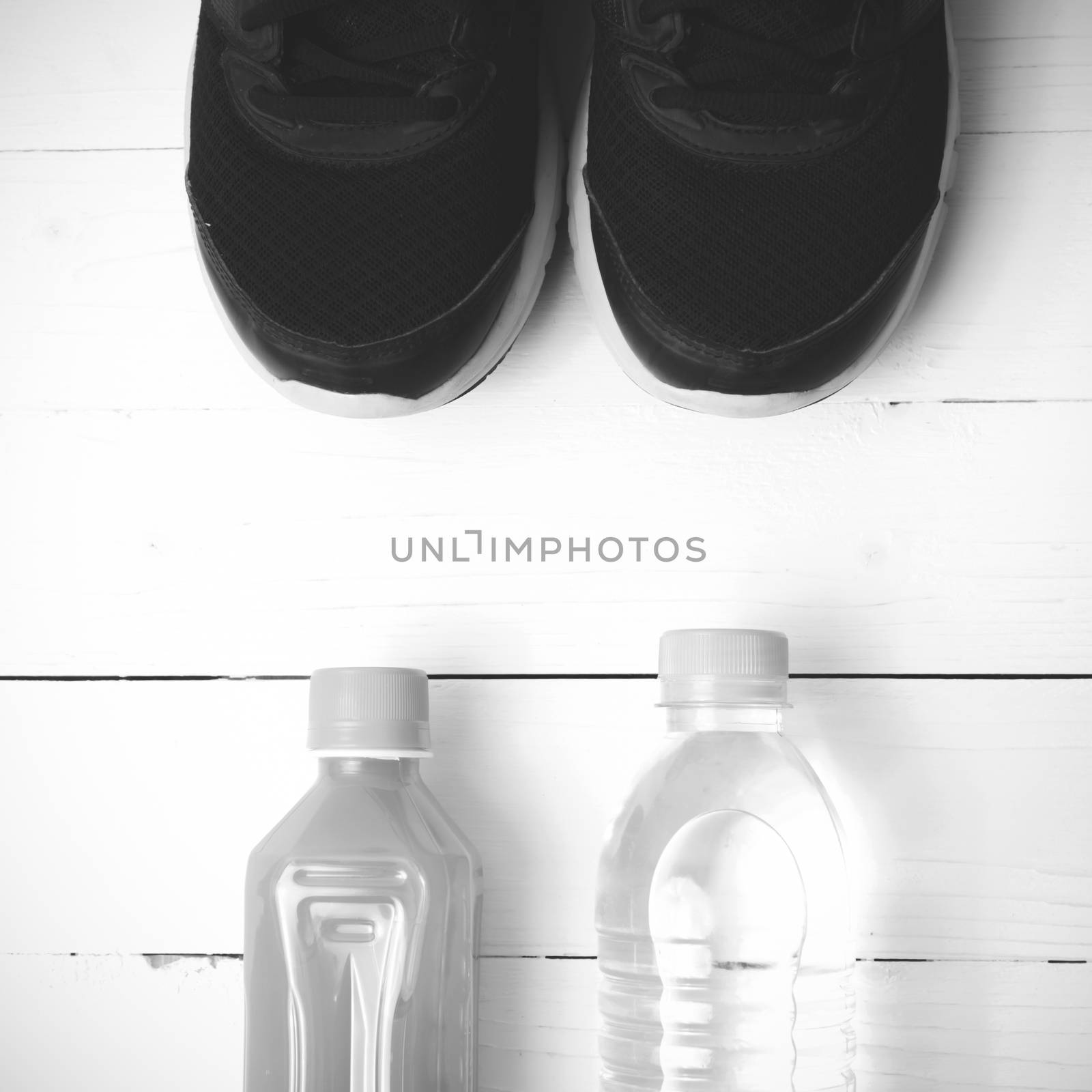 running shoes,drinking water and orange juice on white wood table black and white tone color style