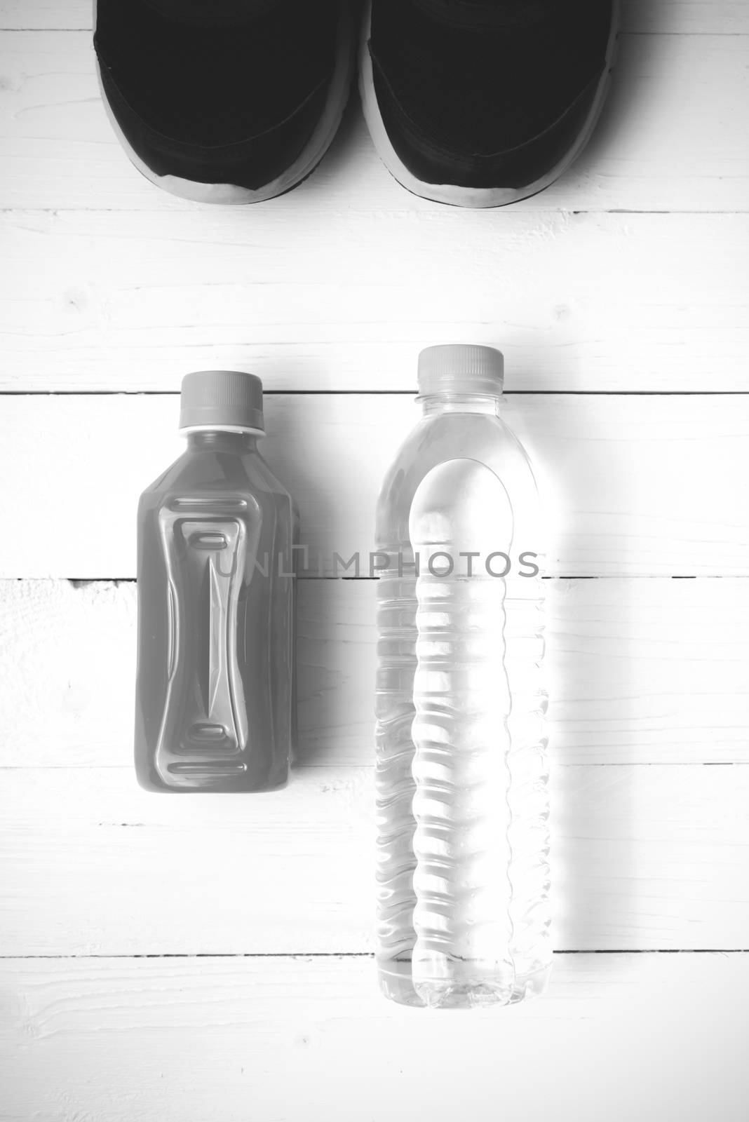 running shoes,drinking water and orange juice on white wood table black and white tone color style