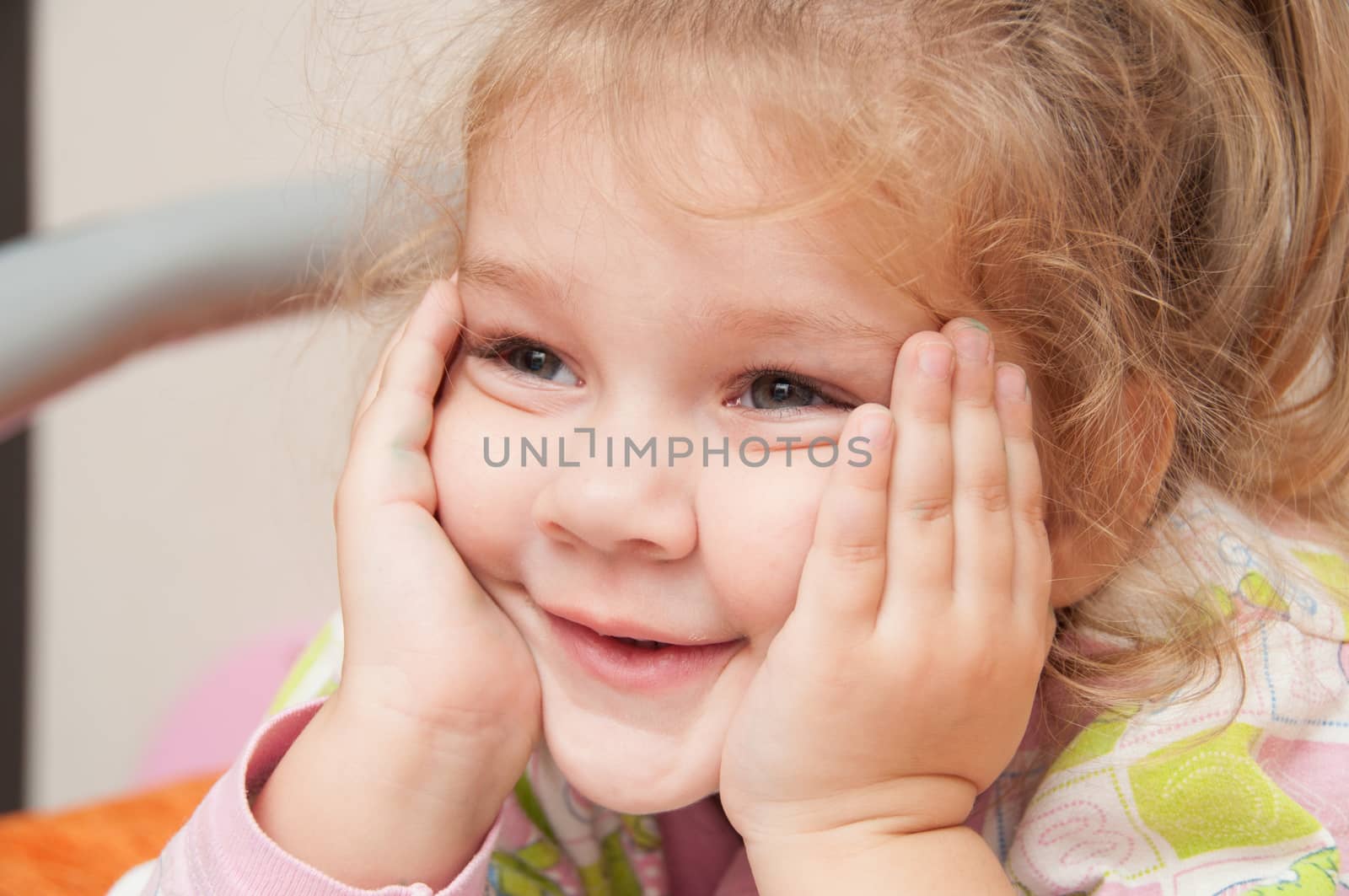 Cheerful three year old girl lying on the bed and looked to the left