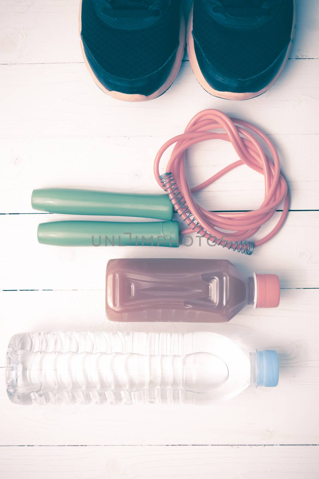 fitness equipment : running shoes,jumping rope,drinking water and orange juice on white wood background vintage tone style