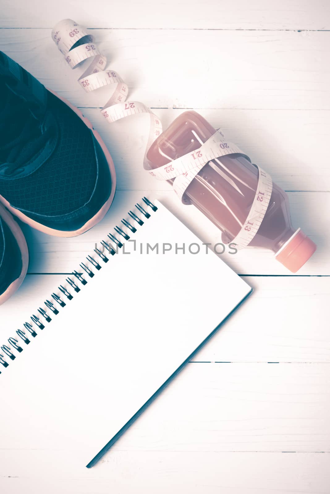 running shoes,orange juice,measuring tape and notepad on white wood background vintage tone color style