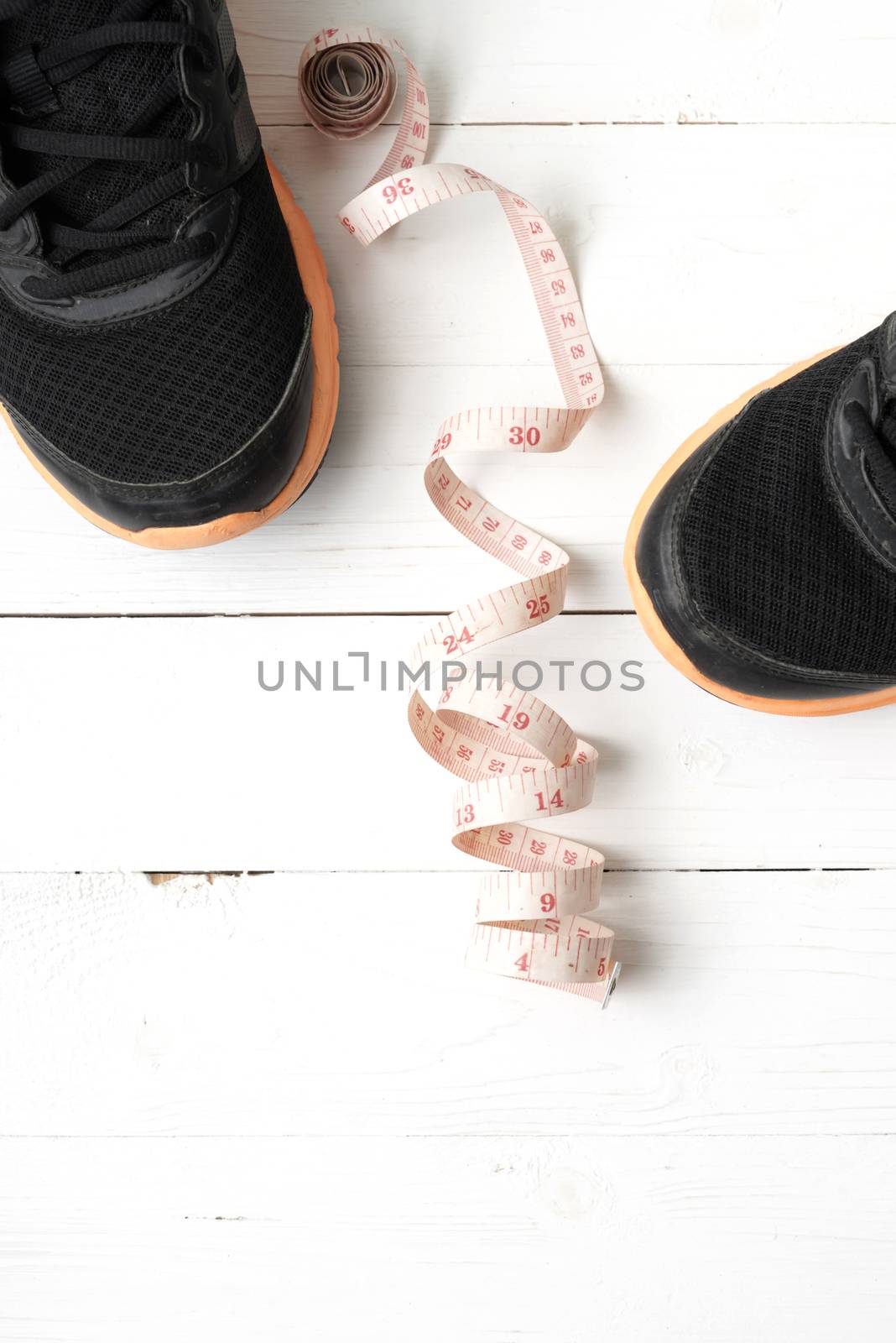 running shoes and measuring tape on white wood table