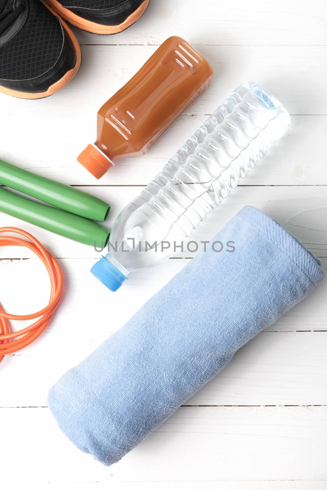 fitness equipment : running shoes,towel,jumping rope,drinking water and orange juice on white wood background
