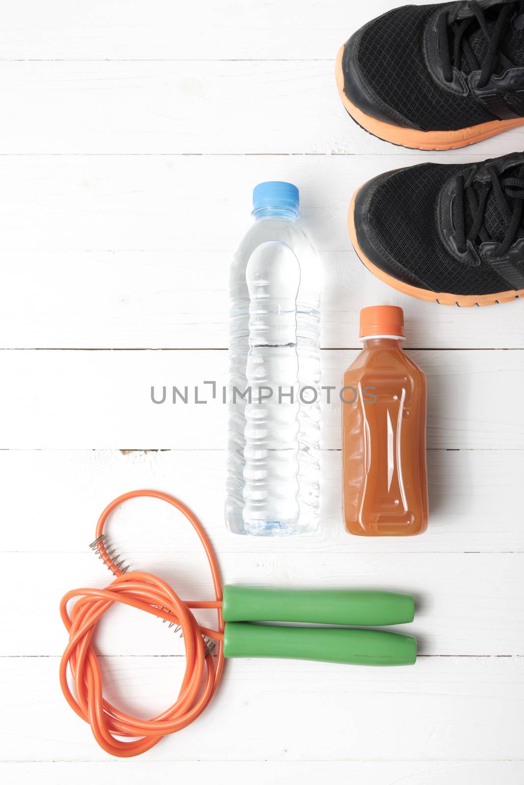 fitness equipment : running shoes,jumping rope,drinking water and orange juice on white wood background