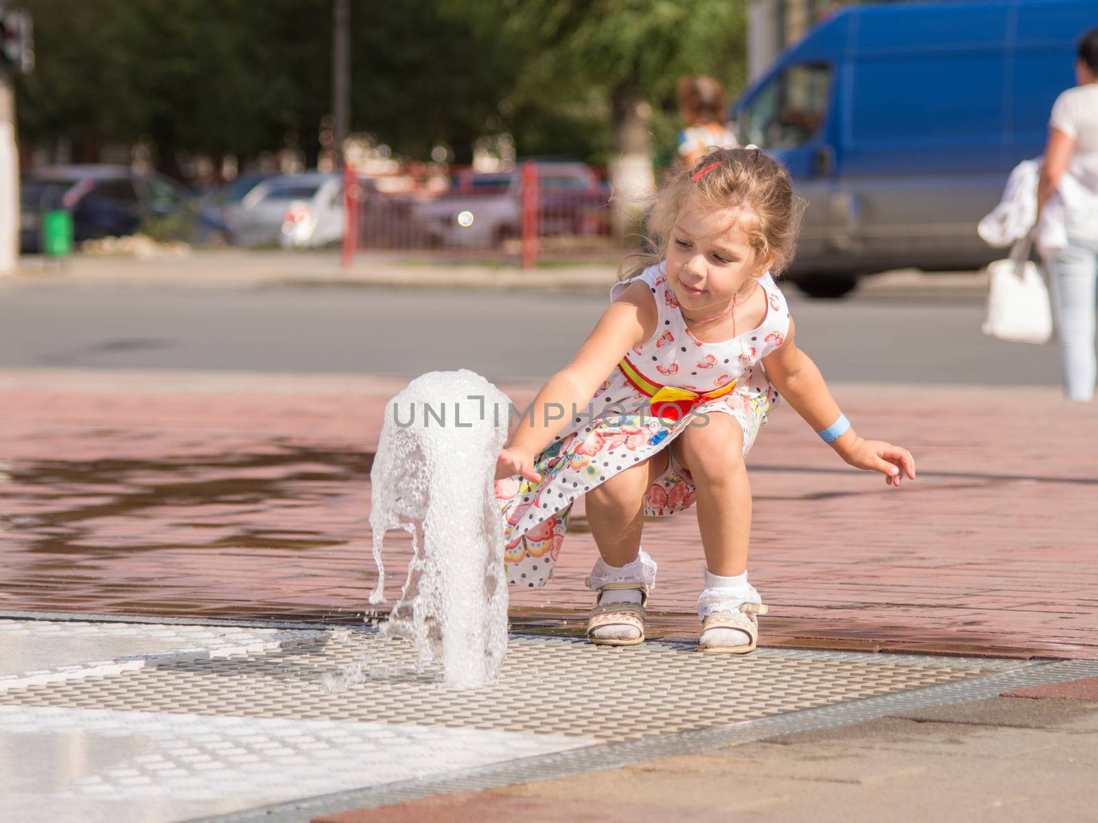 The young girl went to the center of the fountain rises from the earth and touched his hands to the jet fountain