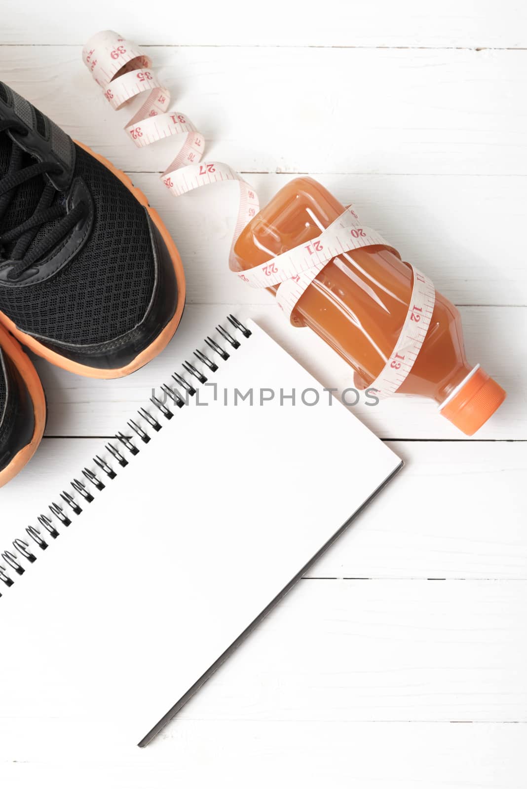running shoes,orange juice,measuring tape and notepad on white wood background