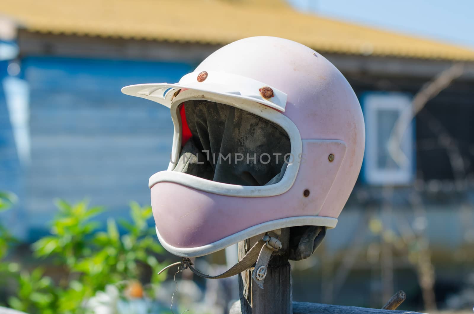 Solodniki, Russia - May 13, 2015: Old helmet on a motorcycle hanging on a stick fence site village house