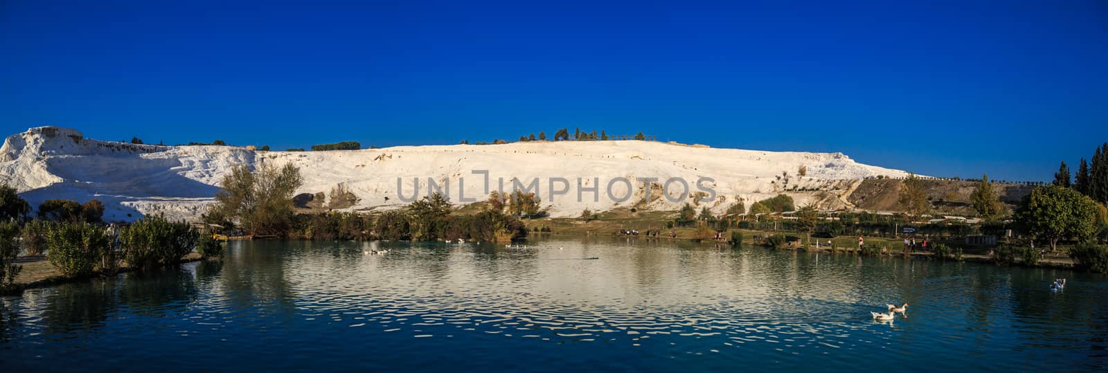 Panoramic view of white hill in Pamukkale and pools on clear sky background, Denizli, Turkey.