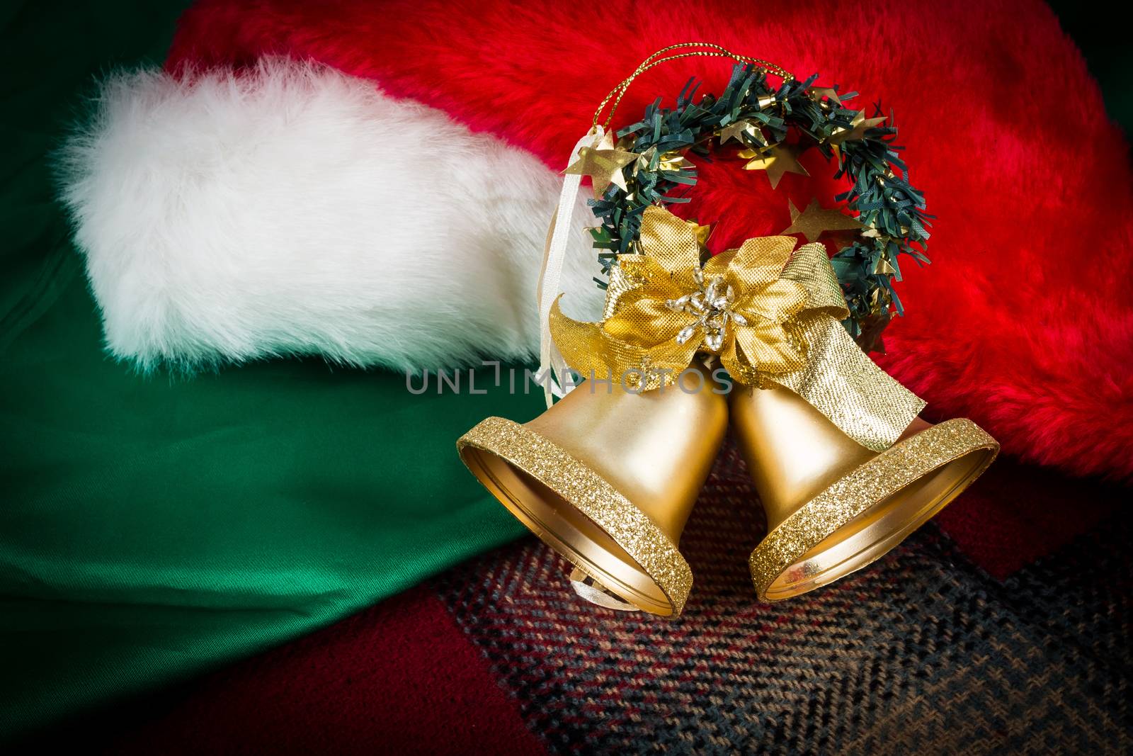 Santa Claus hat and gold bells on green cloth with dark vignette