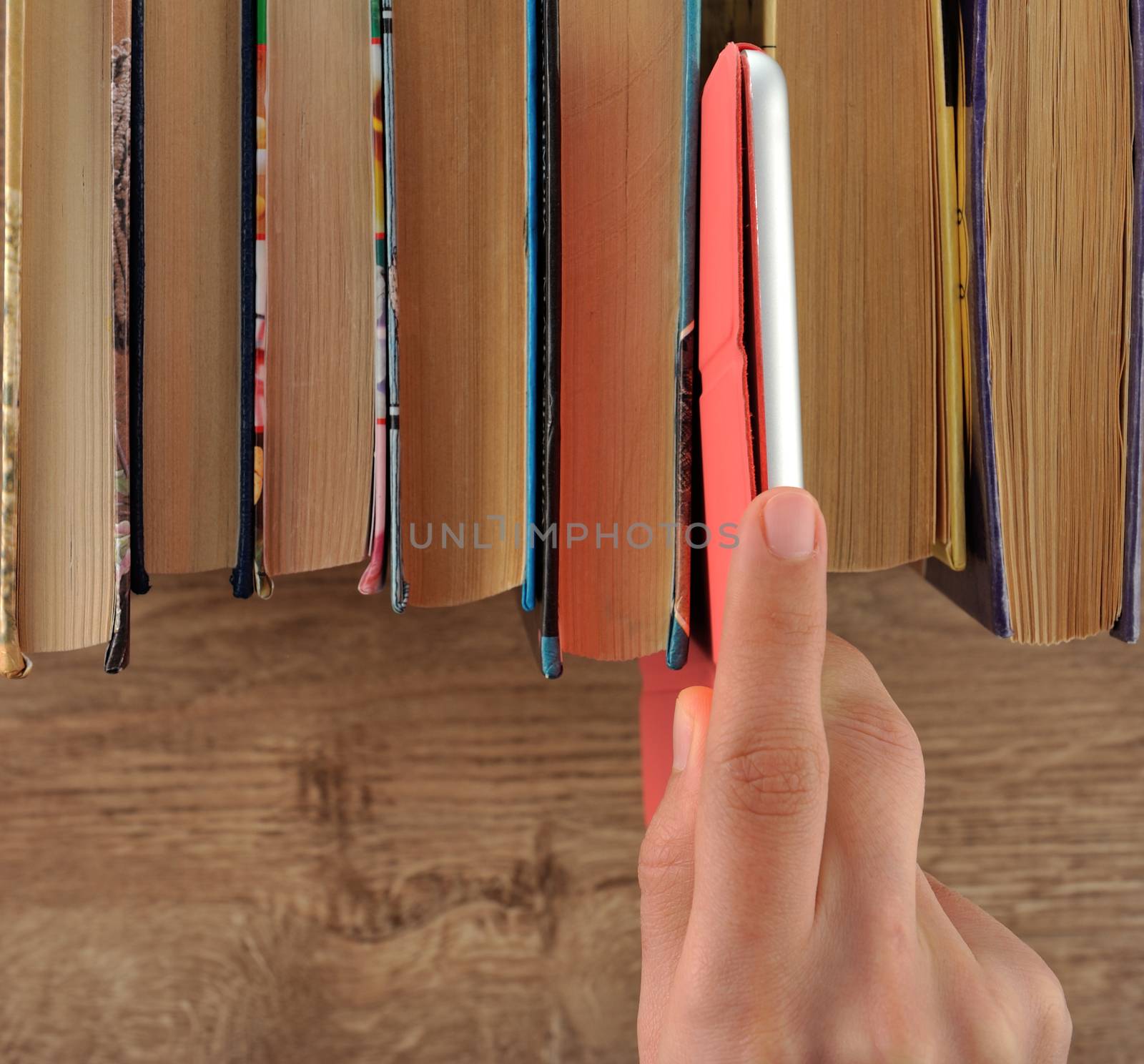Hand taking tablet from bookshelf
