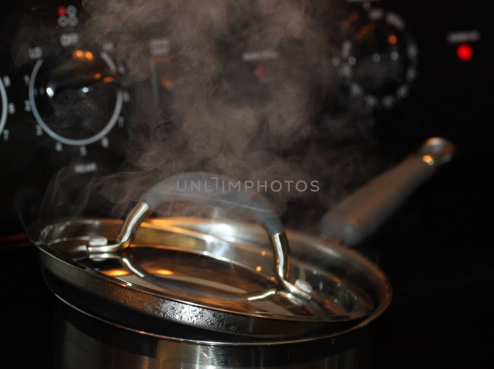 Steam coming out of boiling pot on the hot stove.