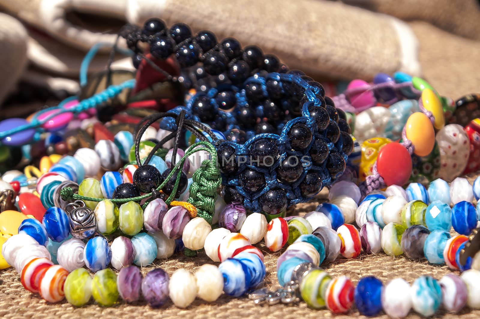 Different bright, multi-colored jewelry of handwork in a sunlight