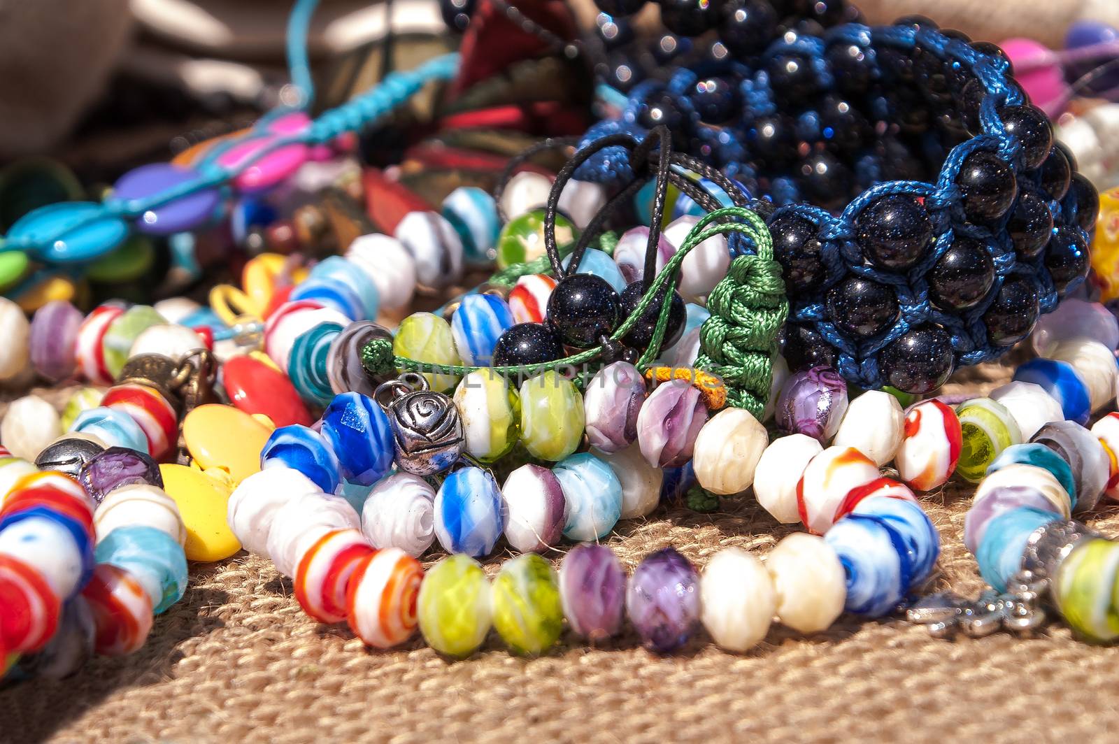 Different bright, multi-colored jewelry of handwork in a sunlight