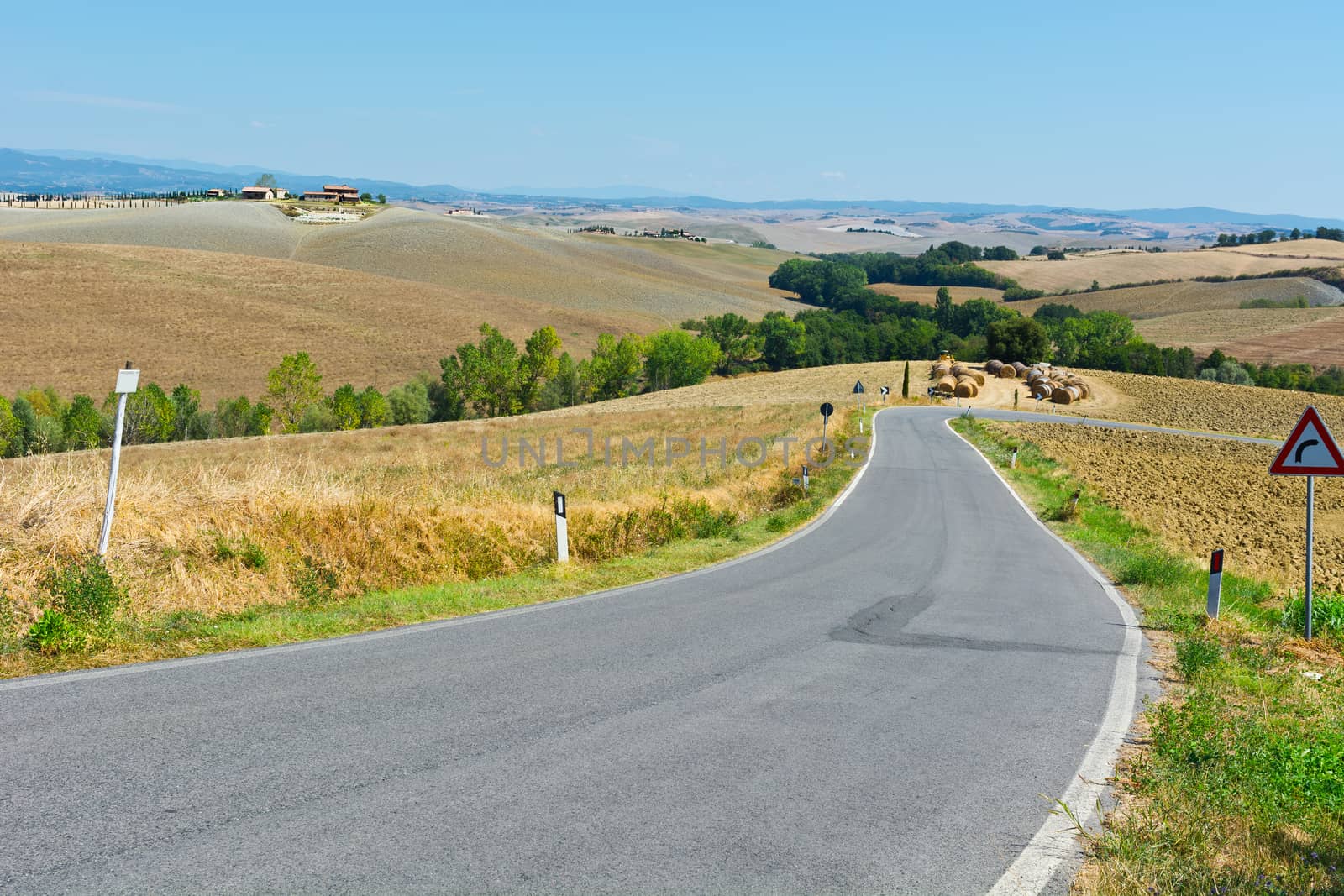 Asphalt Road among Plowed Sloping Hills of Tuscany in the Autumn on the Background of Farmhouses in Italy