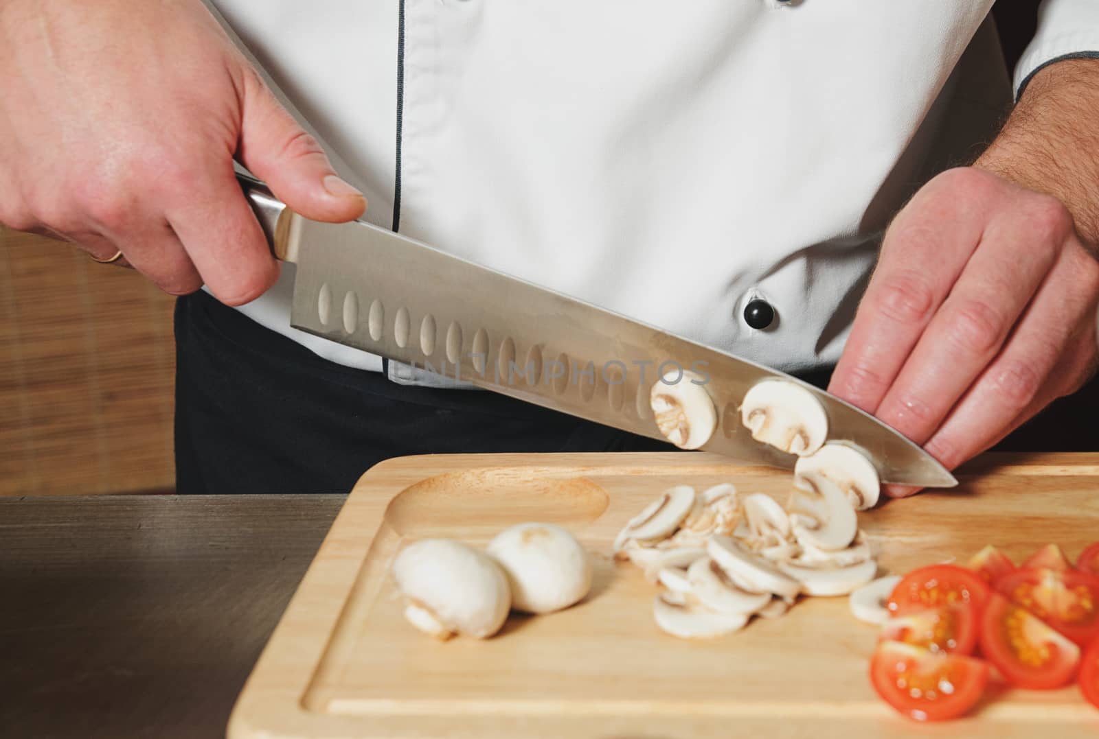 chef cutting mushrooms and tomats on table with knife