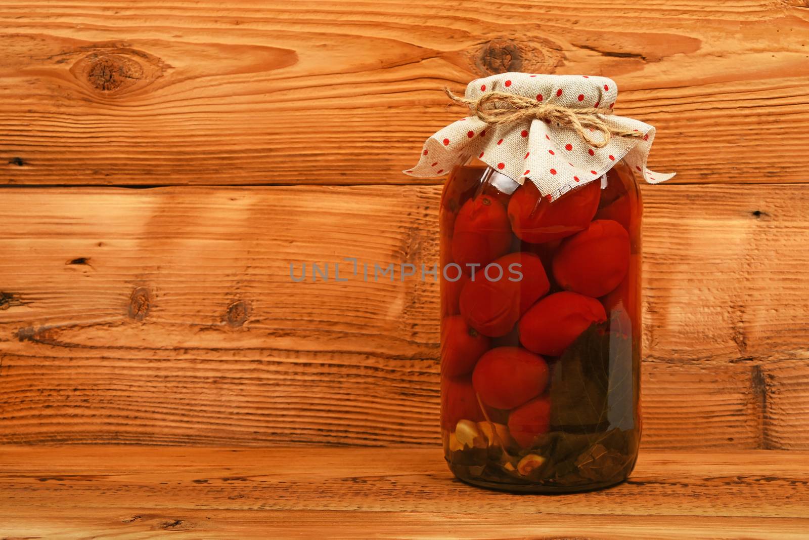 Jar of pickled tomatoes at brown vintage wood surface by BreakingTheWalls