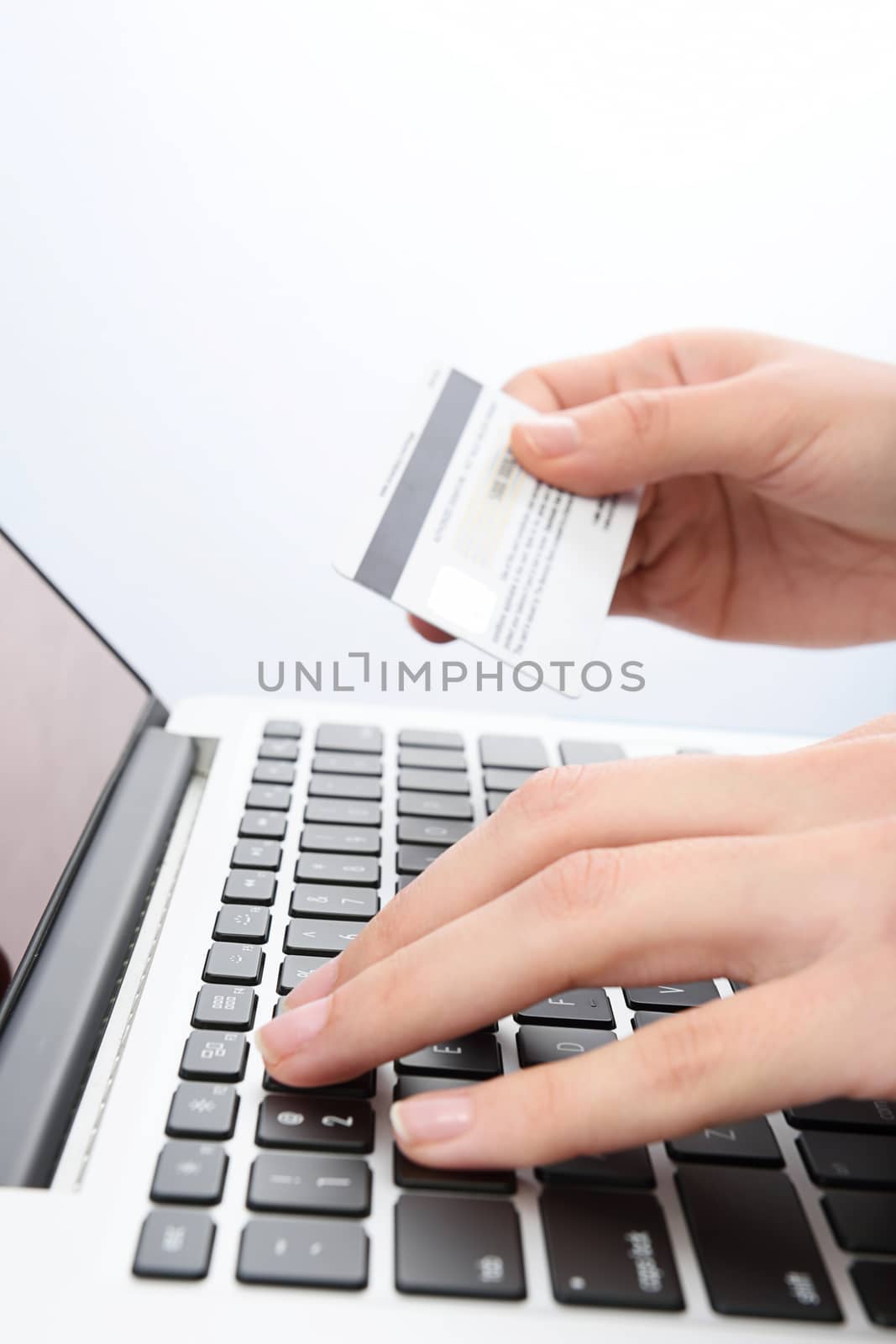 Vertical shot of Human next to laptop with credit card on white background