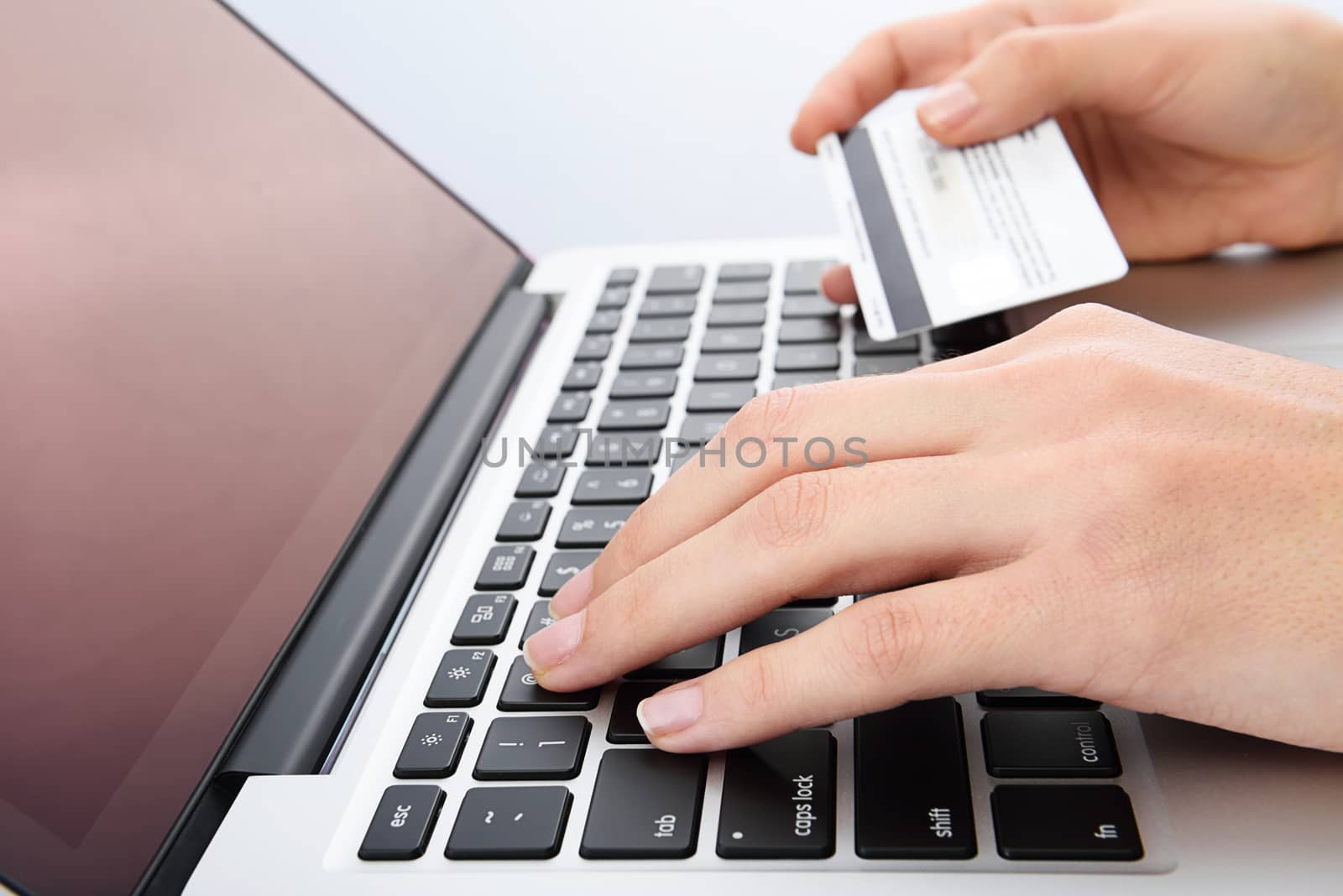 Human next to laptop with credit card on white background