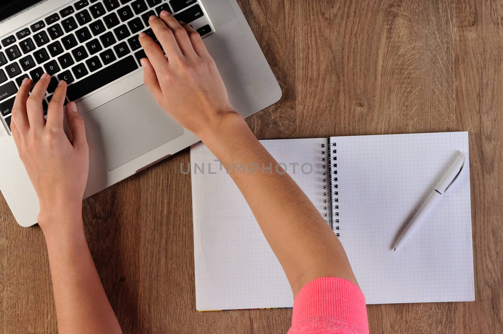 person writing in notebook infront of laptop