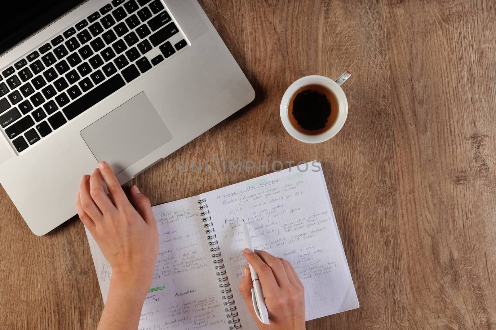 person learning language writing in notebook infront of laptop