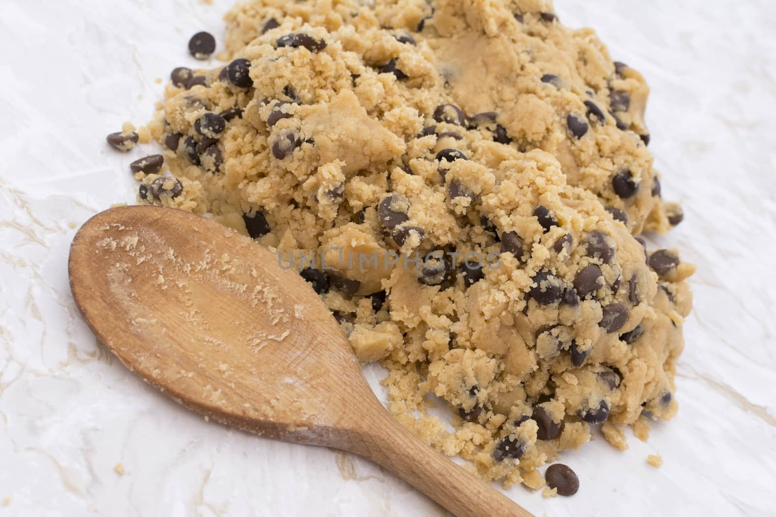 Wooden spoon with chocolate chip peanut butter cookie dough turned out onto a kitchen worktop
