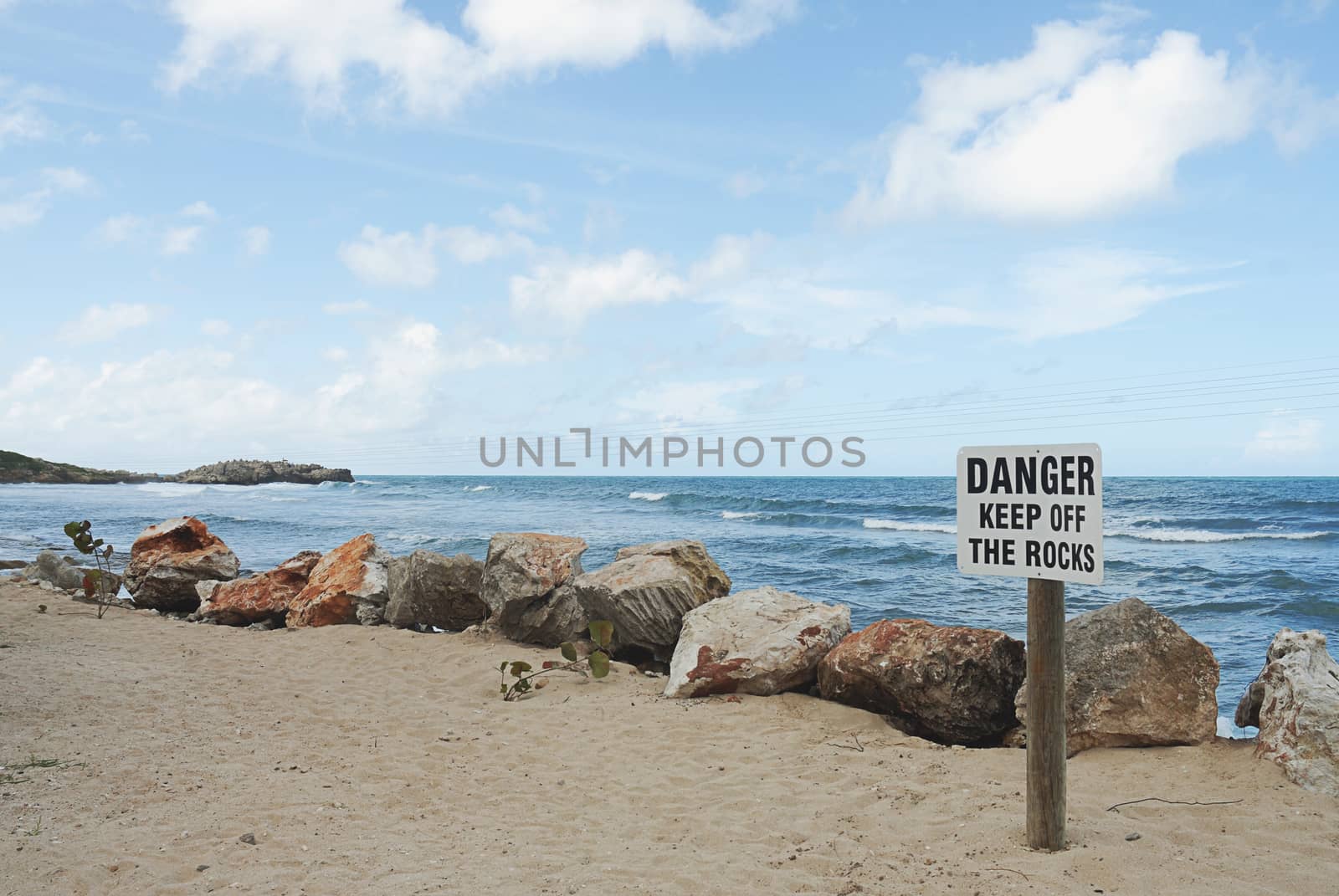 sign on beach with Danger keep off the rocks