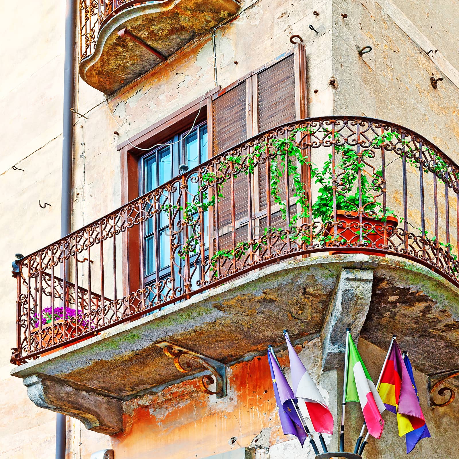 Flags of Italy and the European Union under the Rusty Balcony in the Italian City