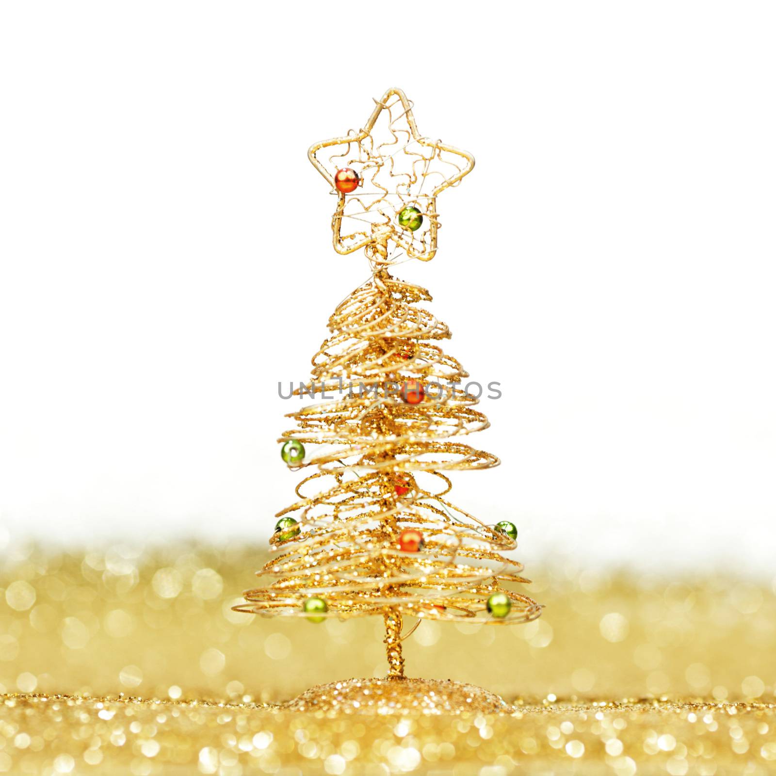 Decorative golden toy christmas tree on glitters isolated on white background