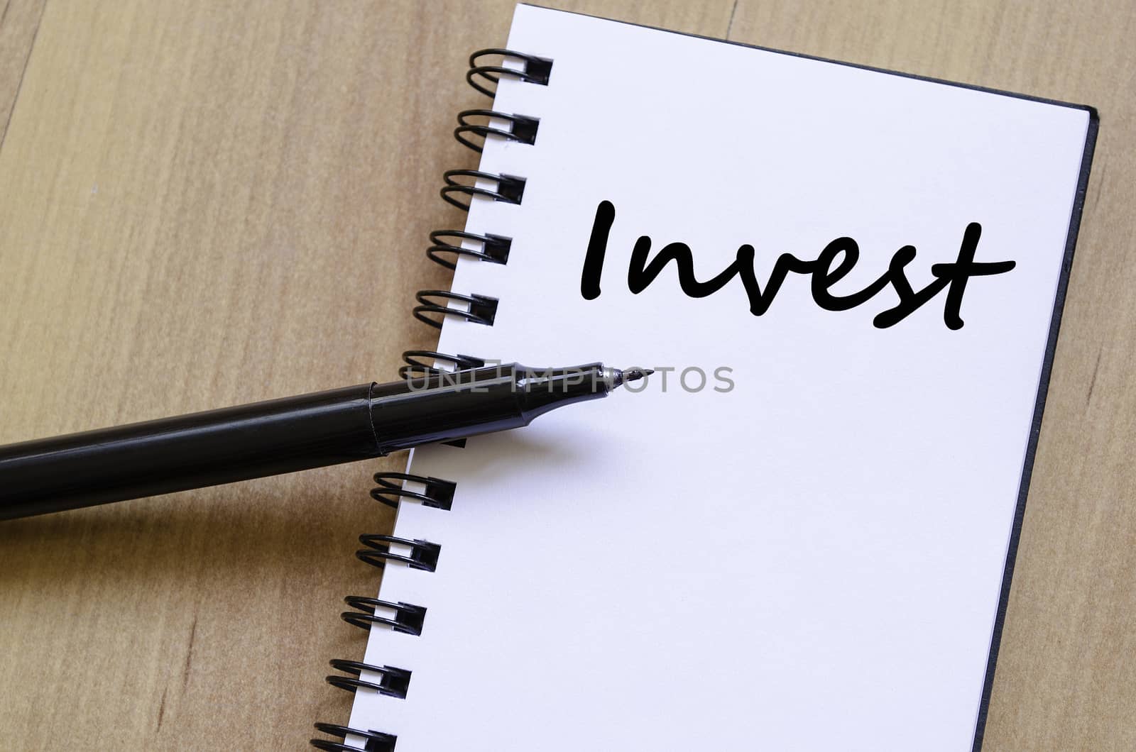 Invest text concept write on notebook with pen