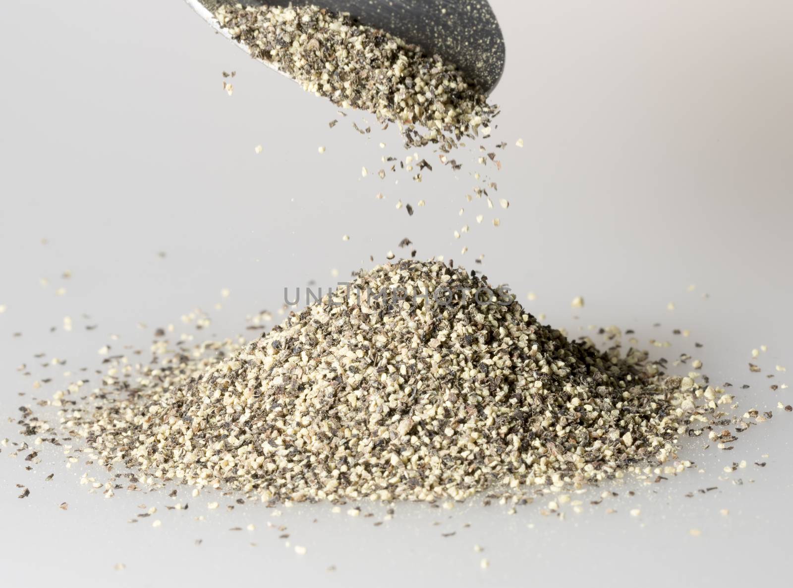 Black Pepper Falling from tablespoon close up.