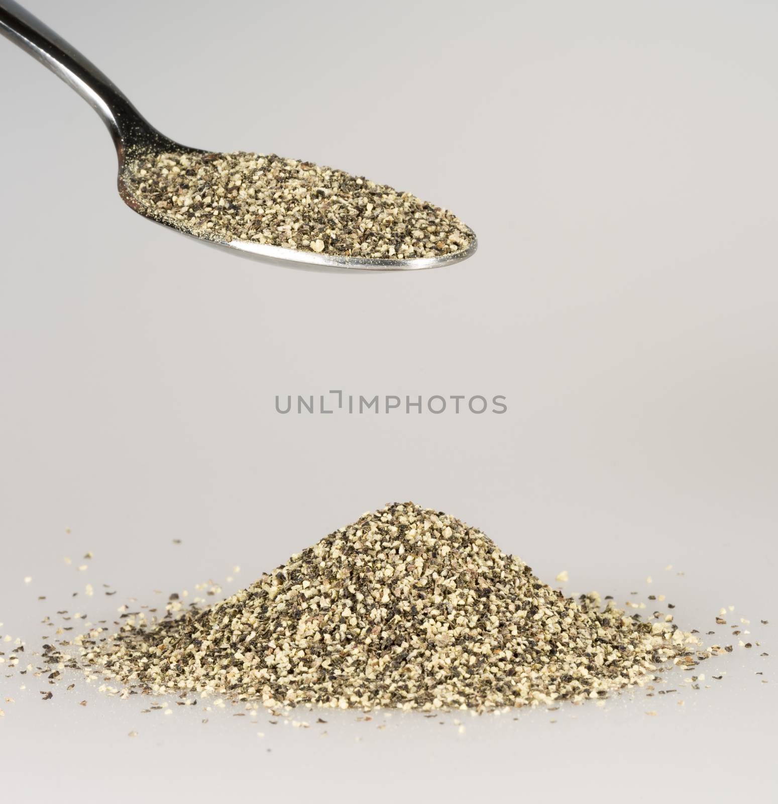 Ground Pepper on Tablespoon with a pile of black pepper beneath.