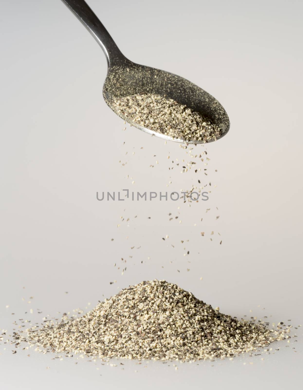 Black Pepper Falling from tablespoon close up.