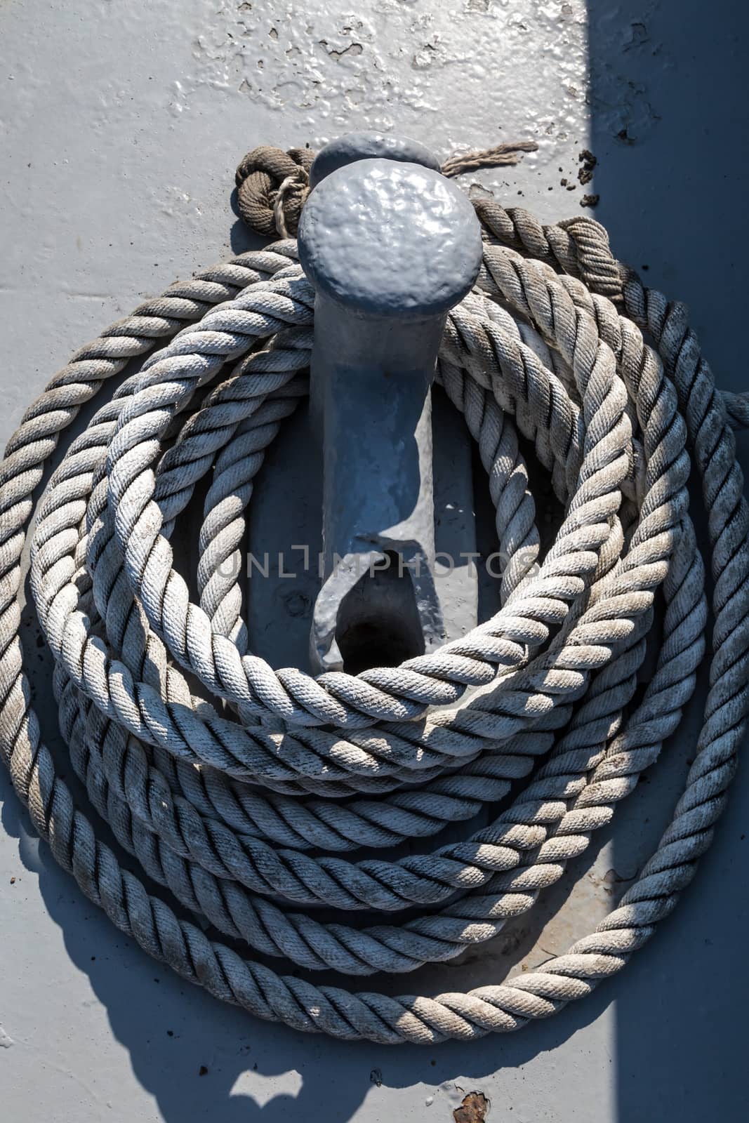 Close up detailed top view of grey nautical rope at an open deck of a ship.