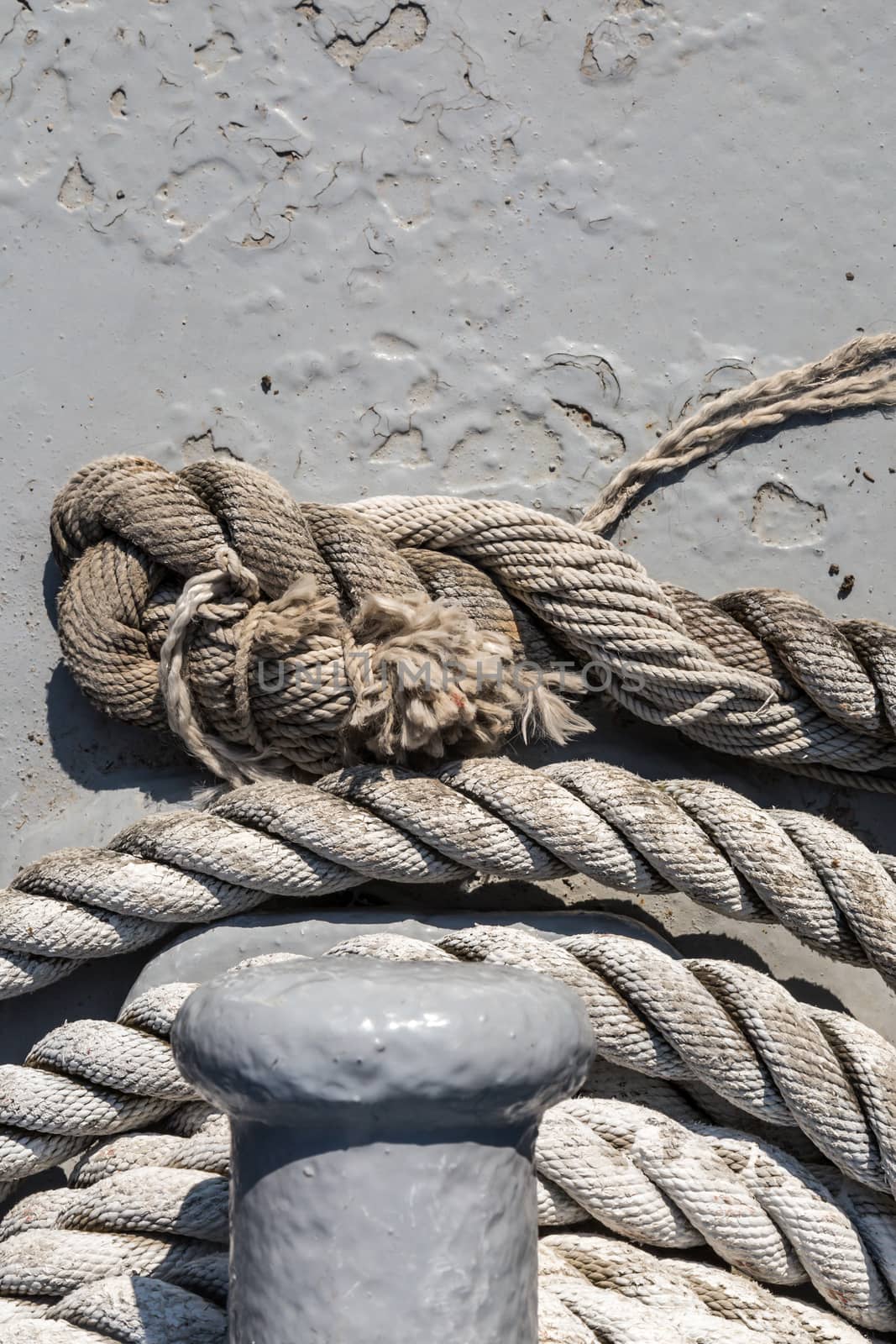 Close up detailed top view of grey nautical rope at an open deck of a ship.