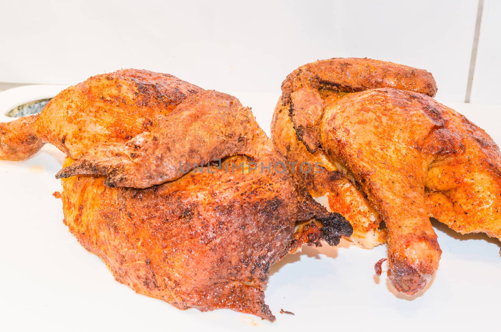 Beautiful brown grilled chicken legs on white plate.