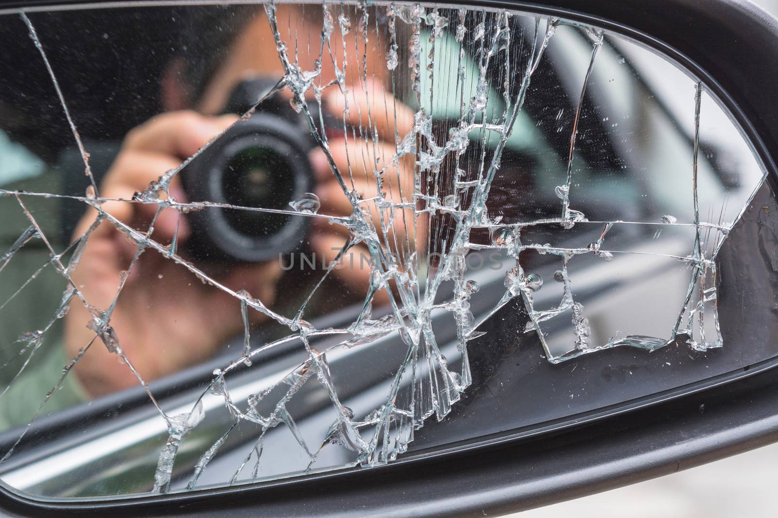 Mirror image of a photographer in the broken car mirror