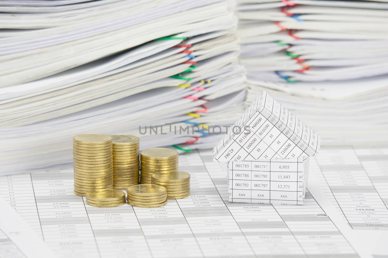 House and step pile of gold coins on finance account have pile of document as background.
