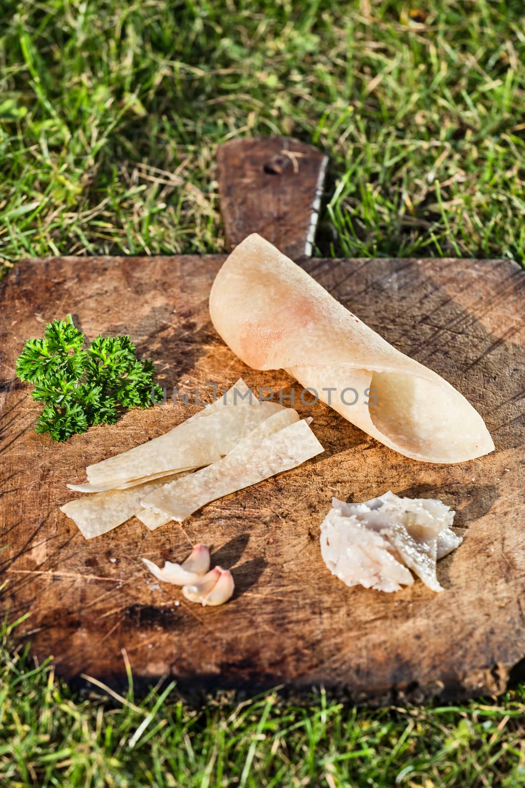 Pig skin slices, garlic and persil on wooden plate