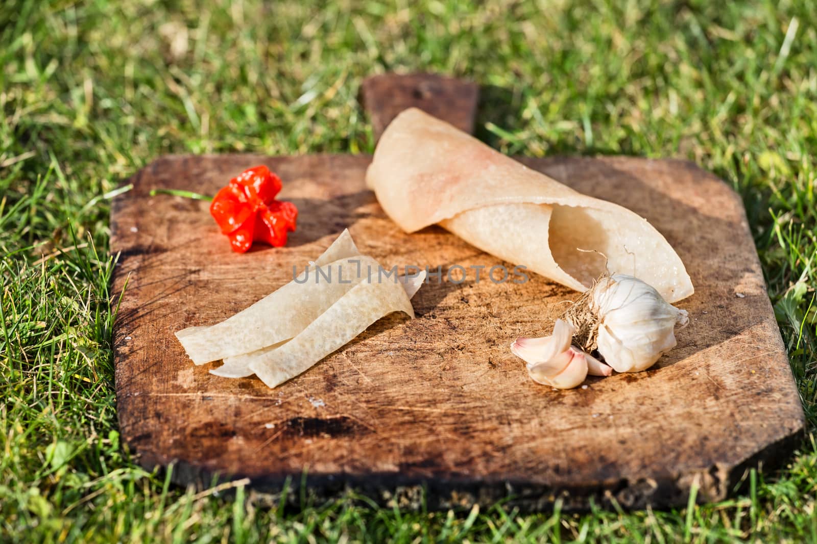 Pig skin slices, garlic and pepper on wooden plate
