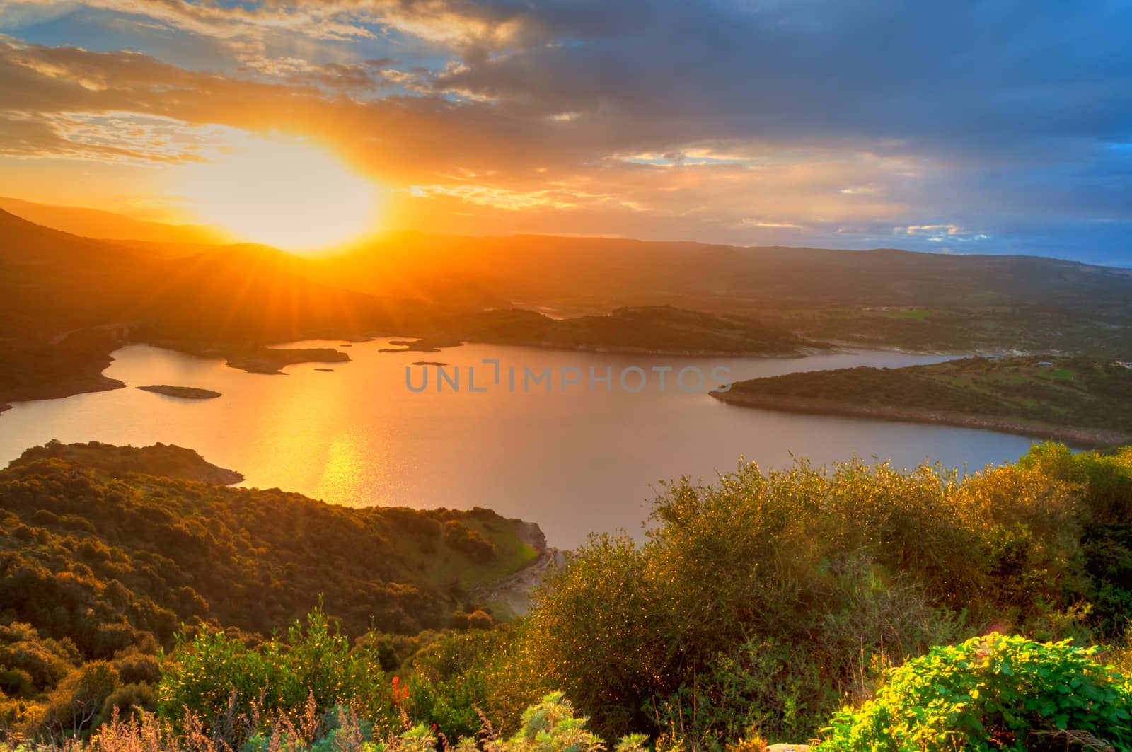 Landscape of sunset on the lake with the sun between the mountains