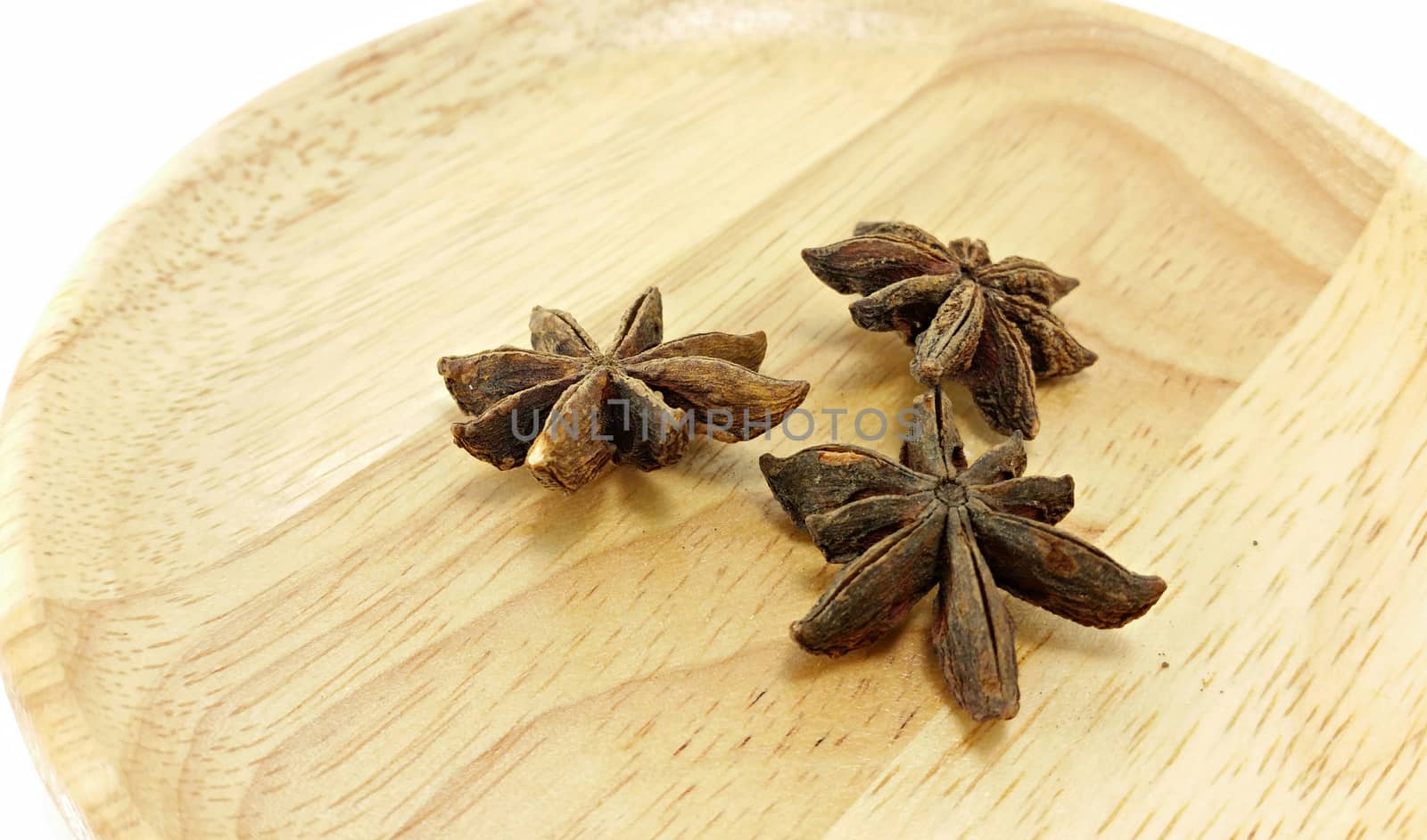 closed up 3 star anises in wooden plate on white background (a little over aperture)