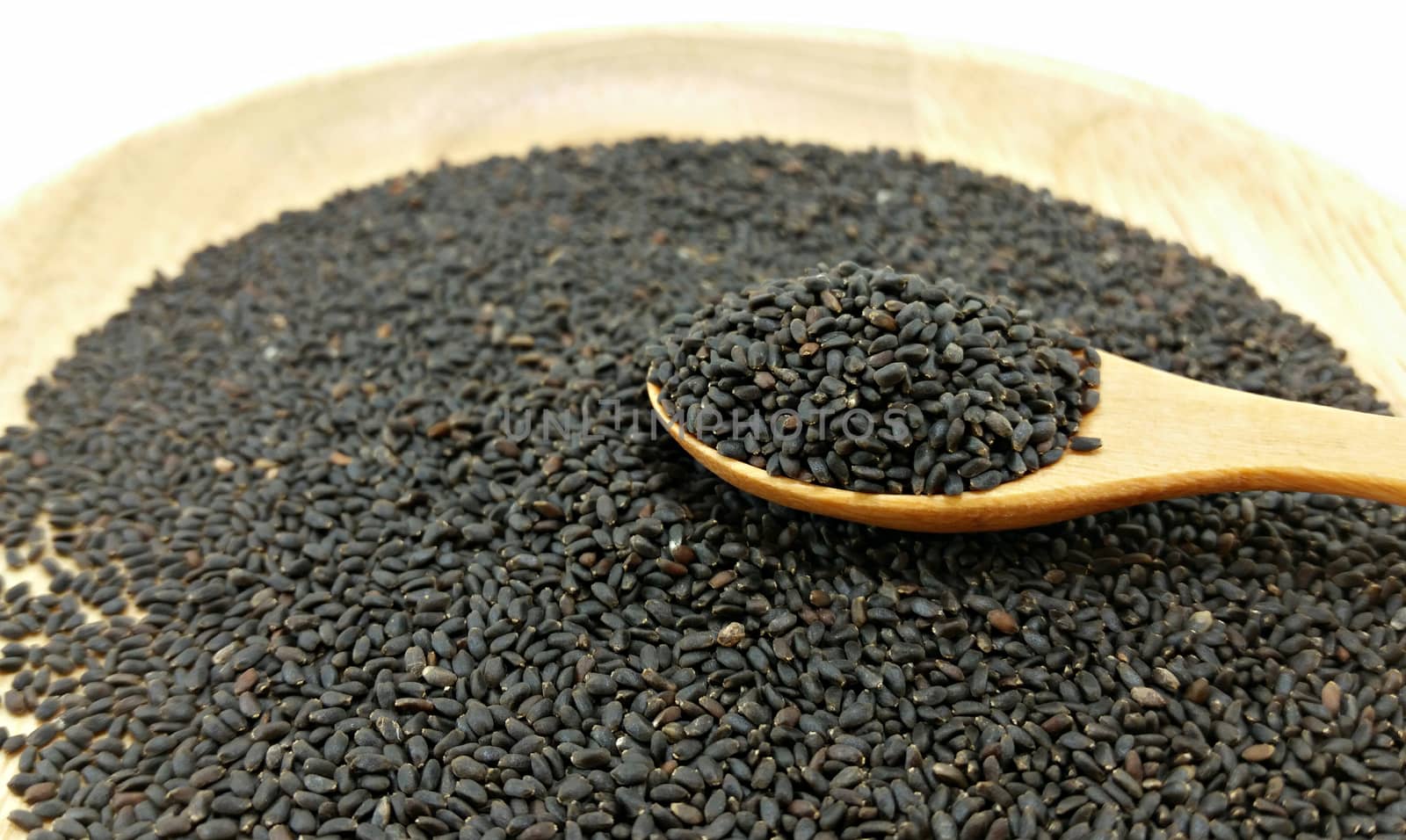 a spoon full hoary basil seed on pile of hoary basil seed on wooden plate