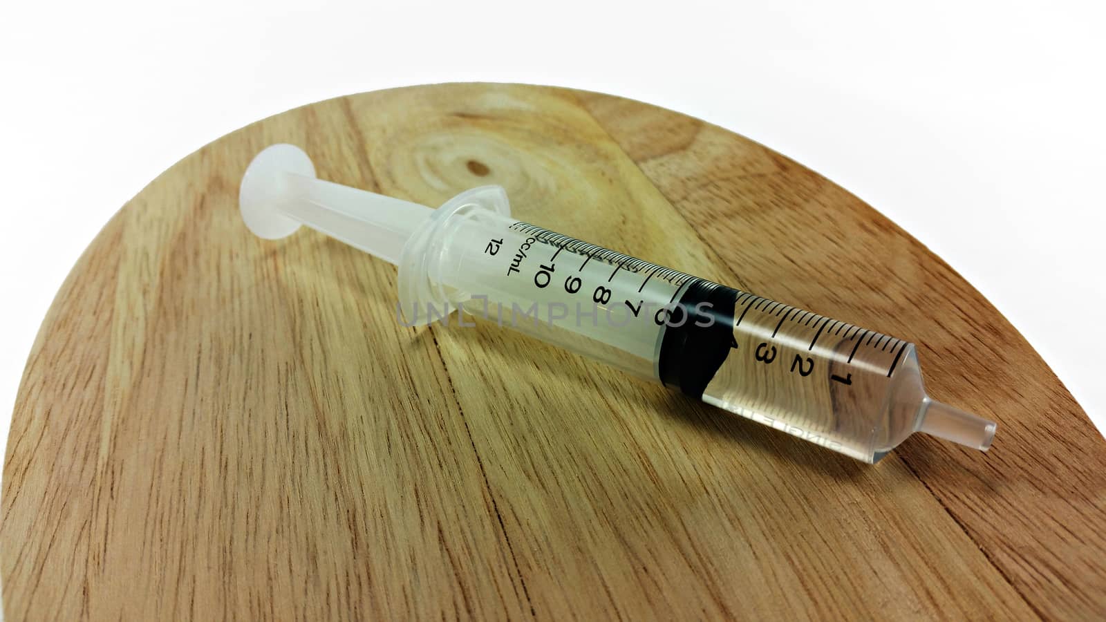 syringe filled with 5cc liquid on wooden plate
