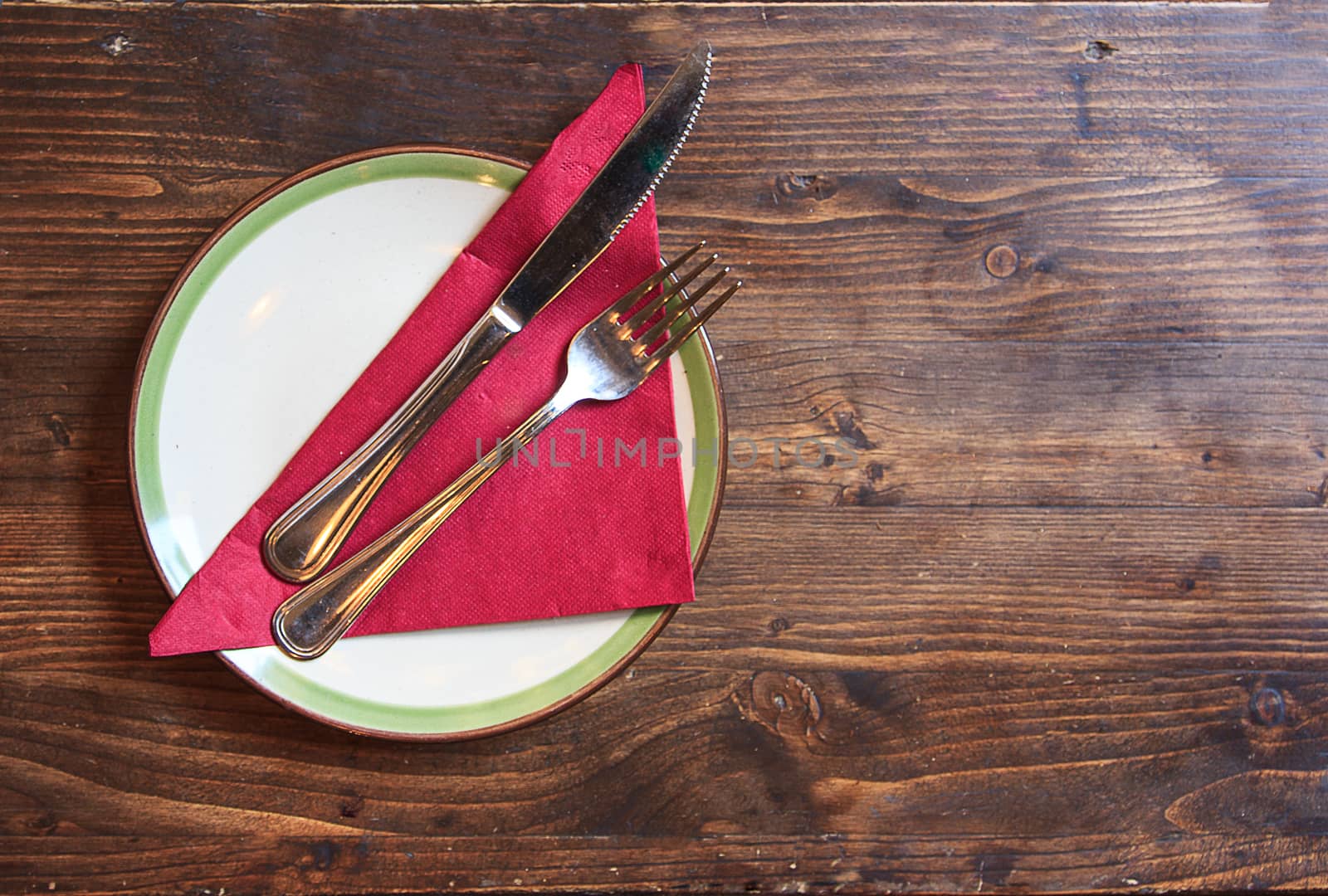 white plate, red napkin and silverware on wooden table
