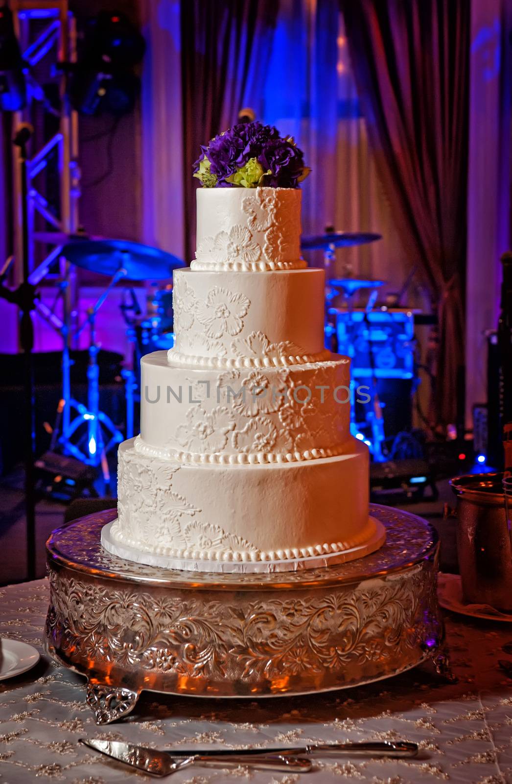 Image of an elegant cream wedding cake with purple flower topper