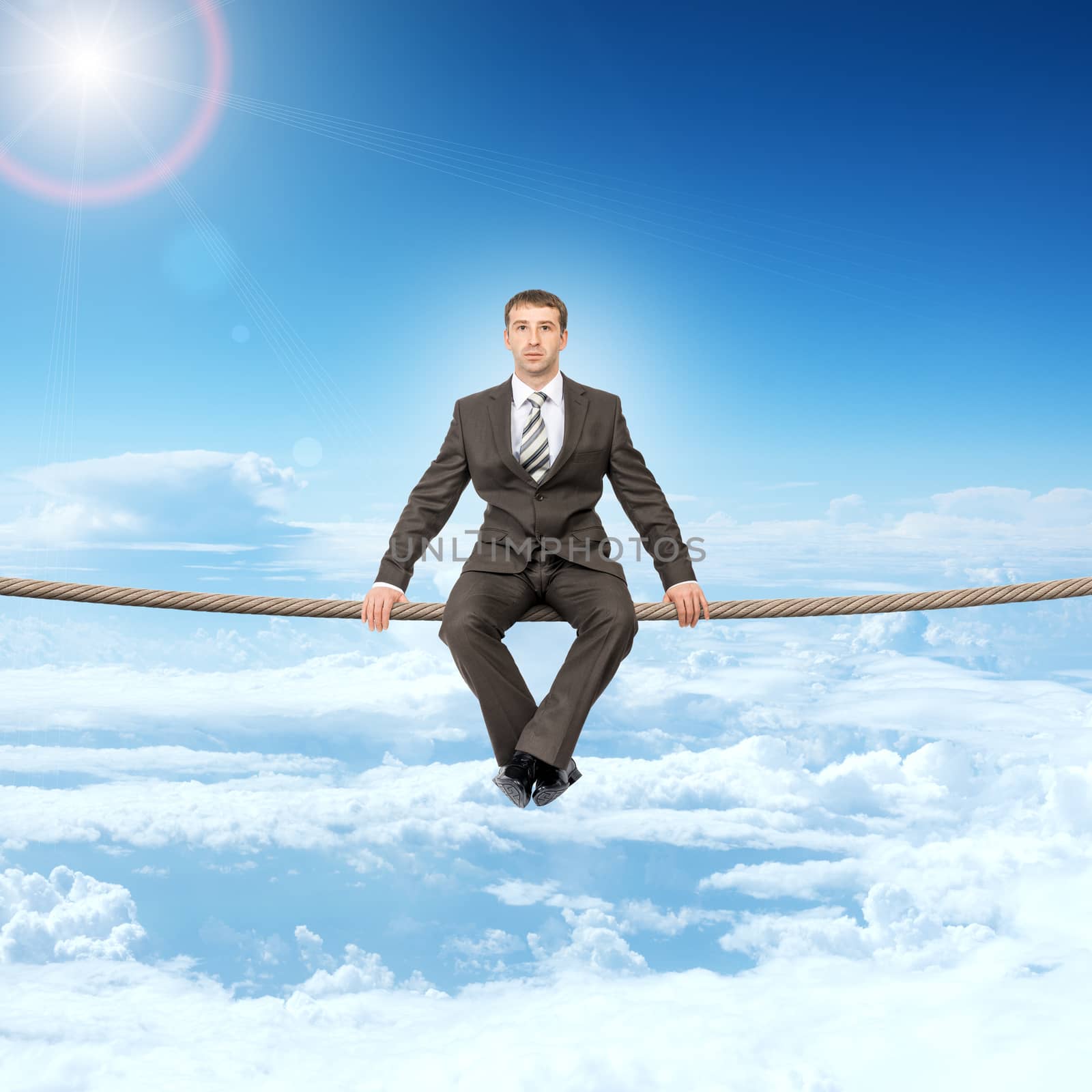 Businessman sitting on rope above clouds and looking at camera