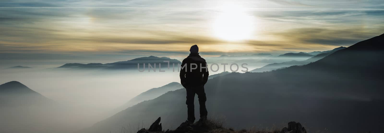Man watching mountains clouds from a peak in the Alps