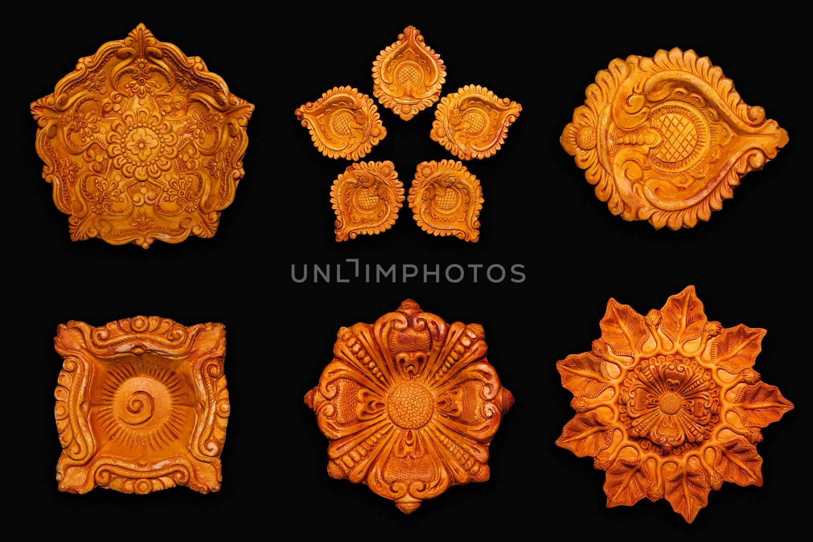 Top view Collage of beautifully carved designer different types of handmade clay lamps isolated on dark background.