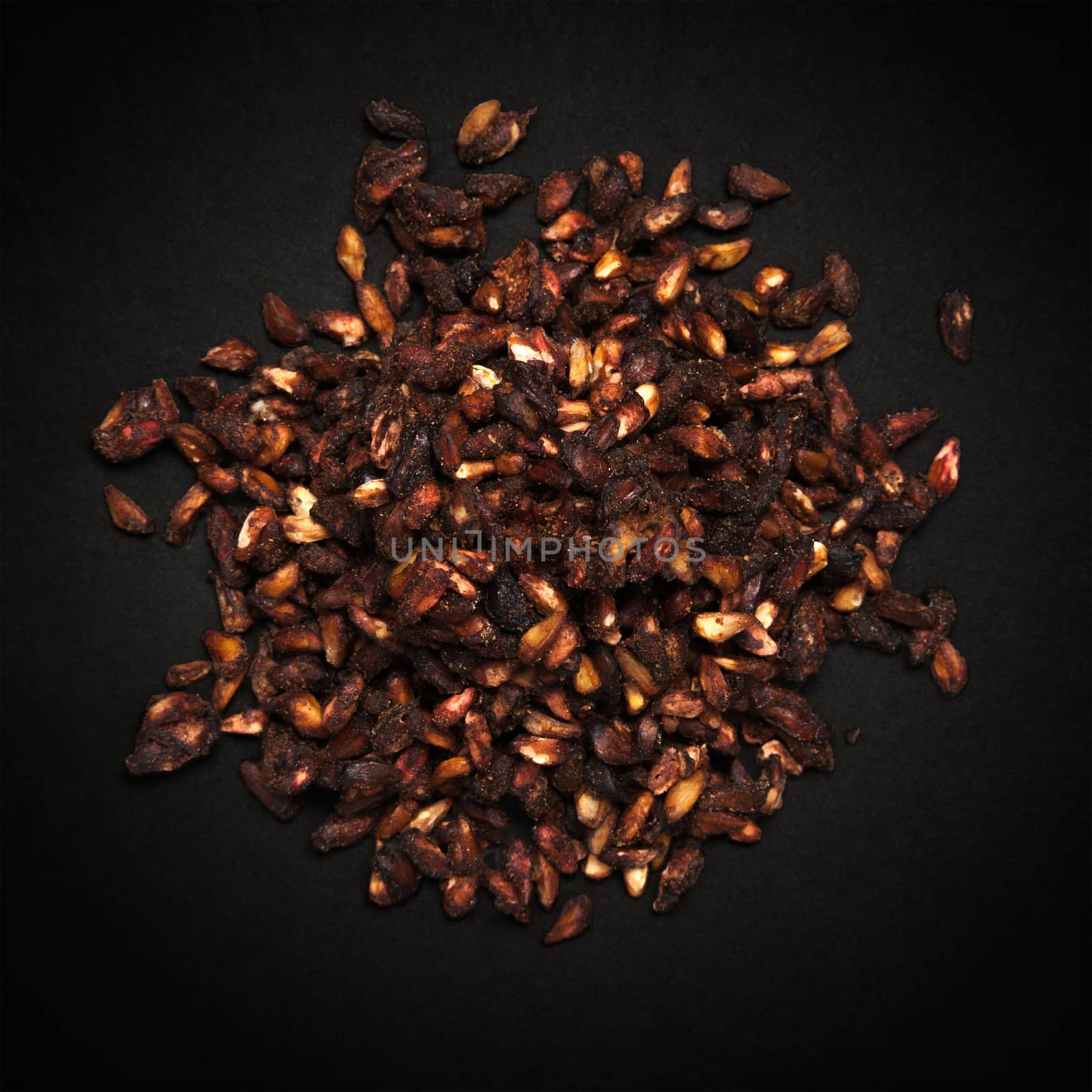 Top view of Organic Dried Pomegranate seeds (Punica granatum) isolated on dark background.